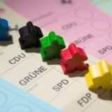 Farbige Spielfiguren stehen am 18.02.2016 in Stuttgart (Baden-Württemberg) auf Wahlscheinen für die Landtagswahl in Baden-Württemberg