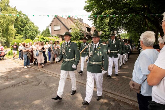 Schützen marschieren auf der Straße an Schaulustigen vorbei