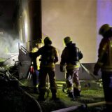 Feuerwehrleute beim Löscheinsatz an der Damaschkestraße, im Hintergrund Rauch, der aus einem Kellerfenster dringt.