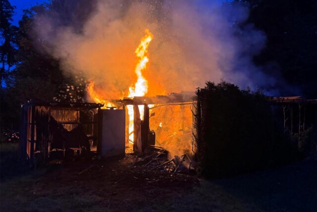 Flammen schlagen aus einer brennenden Gartenhütte.