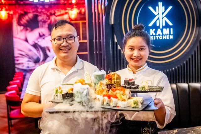 Chef Tri Dung Nguyen und eine Mitarbeiterin halten Sushi-Platten im Restaurant Kami Kitchen am Dortmunder Ostenhellweg in die Kamera