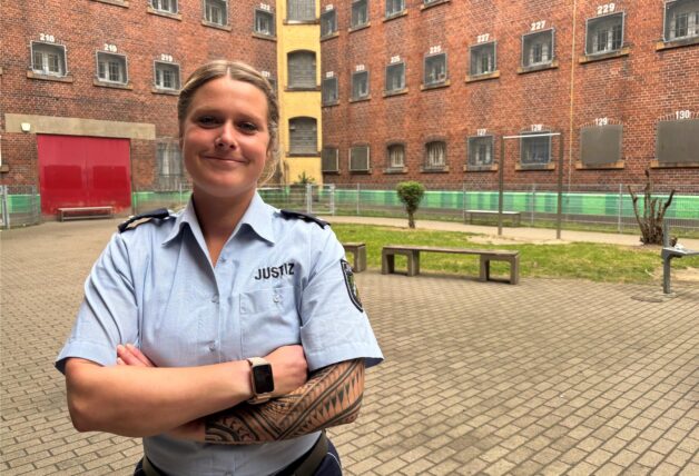 Isabelle Lymers verschränkt die Arme im Hof der Justizvollzugsanstalt Dortmund, wo sie eine Ausbildung zur Justizvollzugsbeamtin macht.