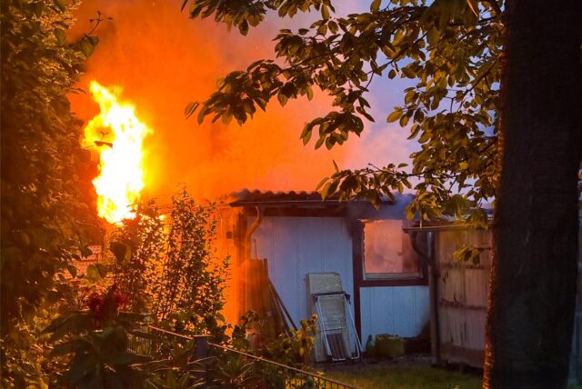 Flammen schlagen aus einer brennenden Gartenhütte.
