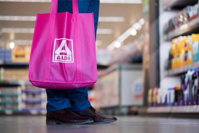 Ein Mann steht mit einer pinken Aldi-Nord-Einkaufstasche vor einem Regal in einem Aldi-Markt.