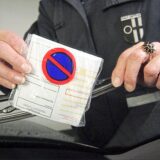 Eine Politesse klemmt einen Strafzettel unter einen Schreibenwischer.