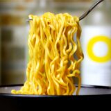 Eine Schüssel mit Instant Nudelsuppe und eine Gabel, auf der sich Nudeln befinden.