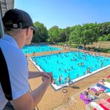 Ein Fachangestellter schaut vom Turm aus auf die gut besuchten Nichtschwimmerbecken im Freibad Mollbeck in Recklinghausen