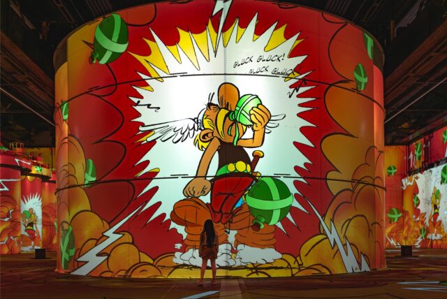 Ein Kind steht vor einer Installation der Asterix-Ausstellung bei Phoenix des Lumières.