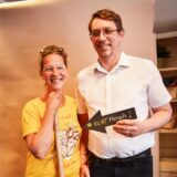 Christina und ein Mann halten ein Schild mit #ECHT Mensch