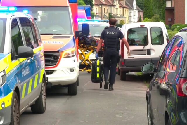 Ein Polizist geht durch die Lippestraße in Lünen, vorbei an Polizeifahrzeug und Krankenwagen.