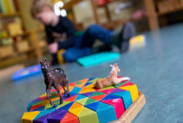 Ein Junge spielt in einem Kindergarten auf dem Boden.