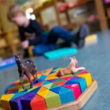 Ein Junge spielt in einem Kindergarten auf dem Boden.