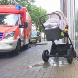 Ein durchnässter Kinderwagen steht neben einem Rettungswagen auf einem Bürgersteig.