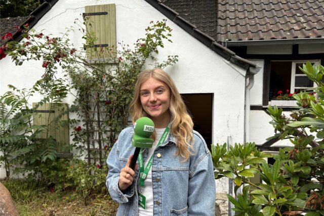 Vivien Caspers steht mit dem Mikro in der Hand vor der Museumsscheune im Alt-Marler Volkspark.