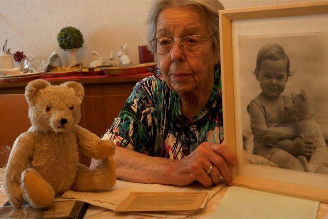Jutta Uellenbeck sitzt an ihrem Esstisch, mit alten Fotos aus ihrer Kindheit.