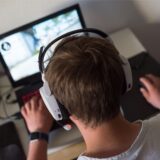 Ein junger Mann sitzt vor einem Laptop und spielt ein Spiel.