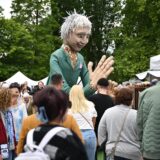 Tag zwei des Kunstmarktes 2025: Eine große Figur wird von einem Mann durch den Hertener Schlosspark getragen.