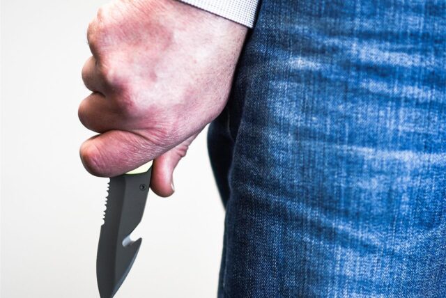 Ein Mann hält ein gezacktes Messer in einer Hand.