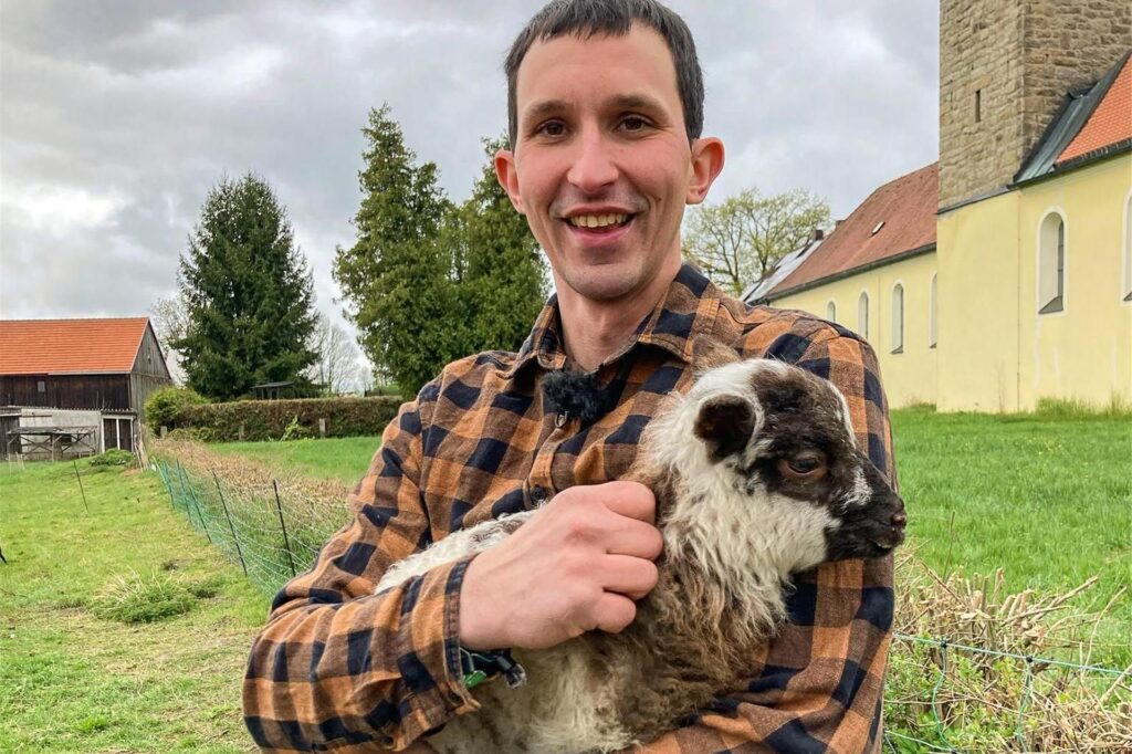 Michael, Teilnehmer von Bauer sucht Frau 2025, hält ein Lamm auf dem Arm.