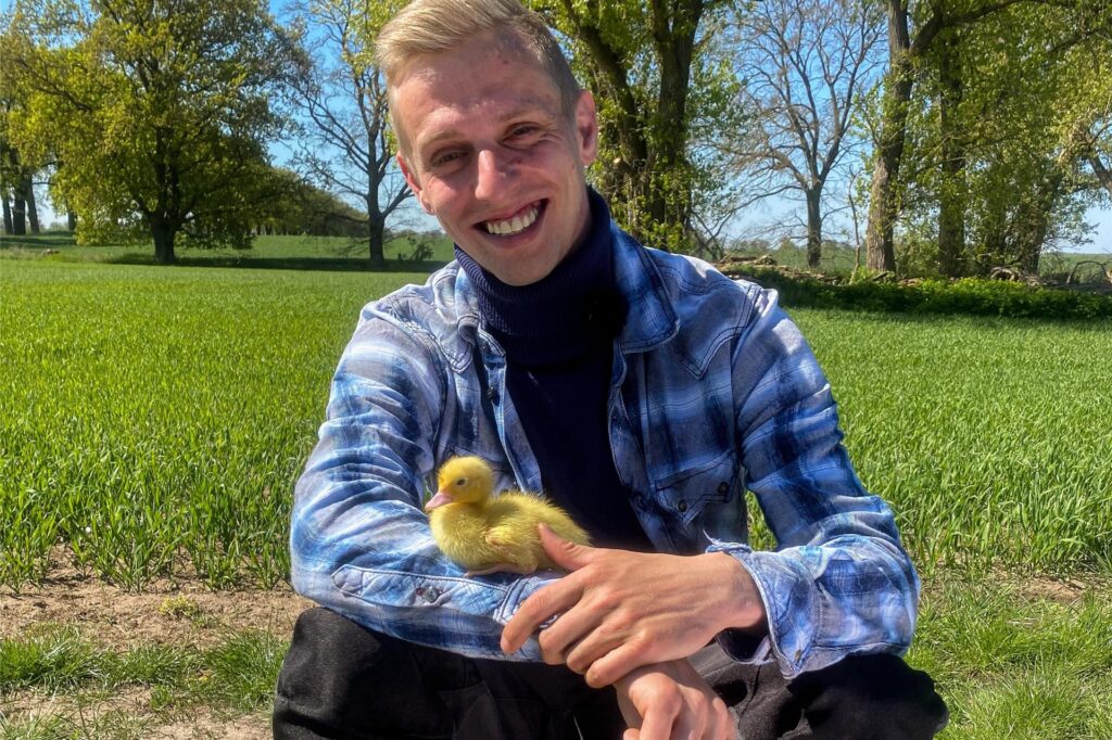 Christopher, Teilnehmer von Bauer sucht Frau 2025, hat ein Küken auf dem Arm.