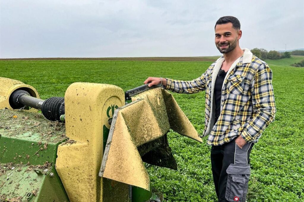 Bastian, Teilnehmer von Bauer sucht Frau 2025, steht neben einer Landmaschine.