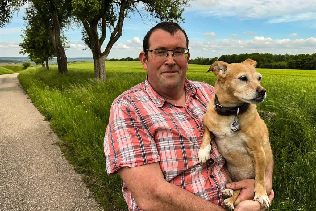 Armin, Teilnehmer von Bauer sucht Frau 2025, hält einen Hund auf dem Arm.