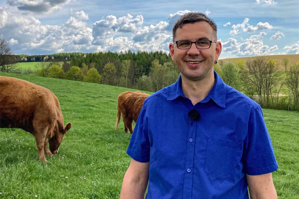 Thomas, Teilnehmer von Bauer sucht Frau 2025, steht auf einer Weide vor zwei Kühen.