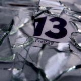 Ein Kalender zeigt Freitag, den 13. – auf dem Kalender liegen Scherben eines zerbrochenen Glases.