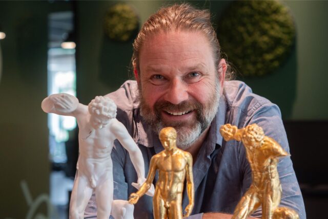 Andreas Weidner steht hinter mehreren kleinen griechisch-römischen Skulpturen.