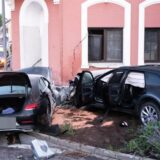 Zwei schwarze Autos stehen schwer beschädigt vor einem haus.