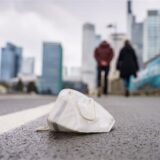 Eine Corona-Maske liegt auf einem nassen Gehweg in Frankfurt.