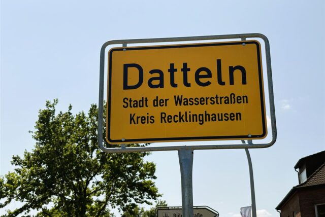 Das Bild zeigt ein gelbes Ortsschild von Datteln, das mit schwarzer Schrift beschriftet ist. Unter dem Ortsnamen steht „Stadt der Wasserstraßen“ und „Kreis Recklinghausen“.