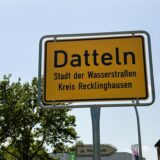Das Bild zeigt ein gelbes Ortsschild von Datteln, das mit schwarzer Schrift beschriftet ist. Unter dem Ortsnamen steht „Stadt der Wasserstraßen“ und „Kreis Recklinghausen“.