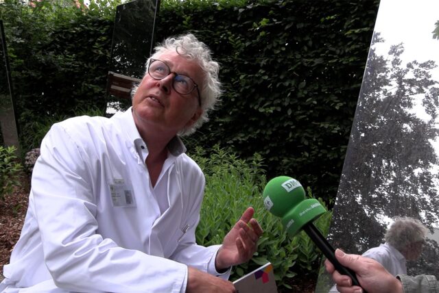 Chefarzt Prof. Dr. Boris Zernikow sitzt im Garten neben einem besonderen Spiegel, der beeinträchtigten Kindern den Blick in den Himmel ermöglicht