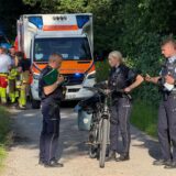 Polizisten mit einem Pedelec, im Hintergrund ein Rettungswagen