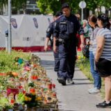 Menschen und Polizisten versammeln sich neben Kerzen und Blumen vor einer Schule in Graz, Österreich, wo ein ehemaliger Schüler zwei Tage zuvor das Feuer eröffnet hat.