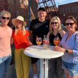 Drei Frauen und zwei Männer stehen bei der After-Work-Party am Imbiss am Schacht auf dem Gelände der Zeche Schlägel & Eisen in Herten-Langenbochum an einem Stehtisch nebeneinander.