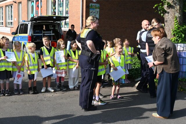 Polizei mit Kindern und einer Frau an einer Schule