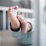 Die Füße eines Babys sind in einem Kinderbett zu sehen. (Symbolbild)