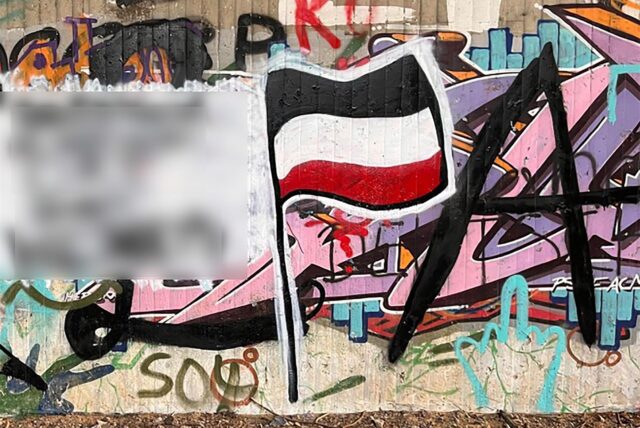 Eine Wand mit Graffiti, darunter eine Reichsflagge.