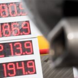 Die Preise für Diesel und Benzin E10 stehen an einer Tankstelle hinter einem parkenden Auto, dessen Auspuff im Vordergrund zu sehen ist.