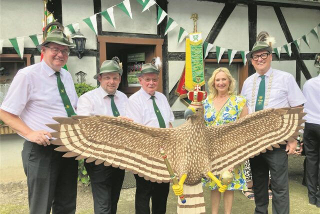 Vier Schützen und eine Schützenkönigin präsentieren einen großen Schützenadler aus Holz.