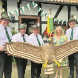 Vier Schützen und eine Schützenkönigin präsentieren einen großen Schützenadler aus Holz.