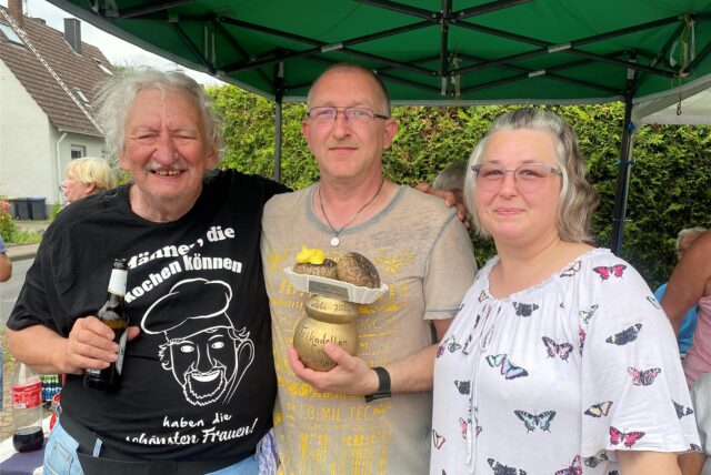 Zwei Männer und eine Frau mit einem Wanderpokal in der Hand.