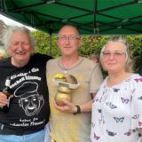 Zwei Männer und eine Frau mit einem Wanderpokal in der Hand.