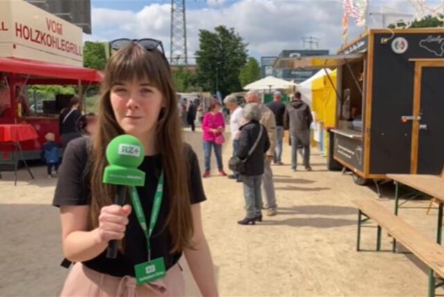 Reporterin Janka Hardenacke berichtet mit Mikrofon in der Hand vom Hafenbecken.