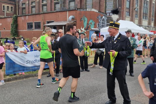 Ein ehemaliger Bergmann überreicht einem Teilnehmer beim Zechenlauf auf der Neuen Zeche Westerholt eine Medaille.
