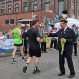 Ein ehemaliger Bergmann überreicht einem Teilnehmer beim Zechenlauf auf der Neuen Zeche Westerholt eine Medaille.