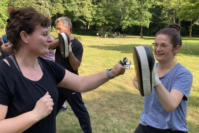 Zwei Frauen beim Training: Die rechte Frau hält eine Pratze, die linke boxt dagegen.