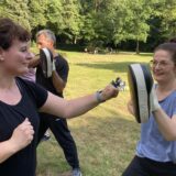 Zwei Frauen beim Training: Die rechte Frau hält eine Pratze, die linke boxt dagegen.